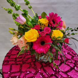 Bright mixed bouquet of roses and gerbera daisies in a glass vase