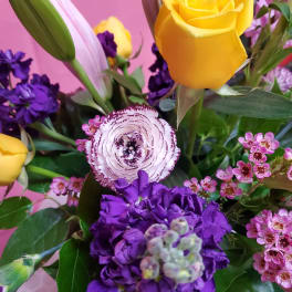 Bouquet with yellow roses, purple blooms, and a pink-striped ranunculus