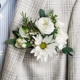 White boutonniere with daisy and rose blooms on a plaid jacket