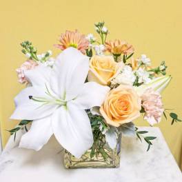 Bouquet of white lilies and peach roses in a glass vase