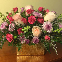 Bouquet of pink and white roses with purple daisies in a gold vase