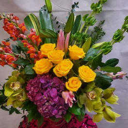 Mixed bouquet with yellow roses, purple hydrangea, and orchids in a vase