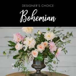 Bohemian floral arrangement in a dark pedestal vase with pale pink and cream blooms