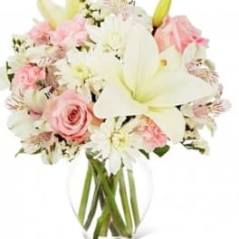 Pink roses and white lilies in a clear glass vase