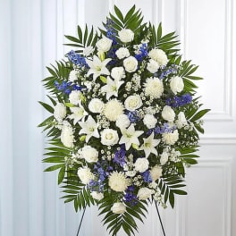 Standing funeral spray of white and blue flowers on an easel