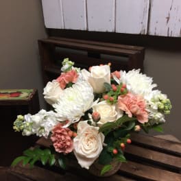 Arrangement of white roses, white chrysanthemums, and pink carnations in a basket