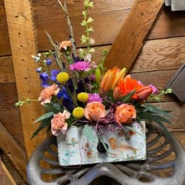 Mixed bouquet with orange roses and colorful blooms in a patterned box