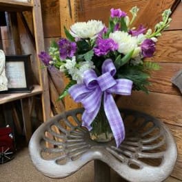 Purple and white floral arrangement with a lavender ribbon in a vase