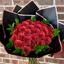 Bouquet of red roses wrapped in black paper with green foliage
