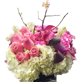 Pink roses and purple calla lilies in a black vase with white hydrangeas