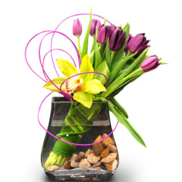 Purple tulips and a yellow orchid in a black glass vase