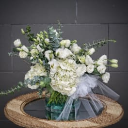 White floral arrangement in a glass vase with a tulle bow