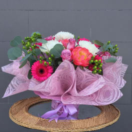 Pink and white mixed bouquet wrapped in pink paper with a purple ribbon