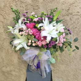 Pink and white floral arrangement in a gray box with tulle ribbon