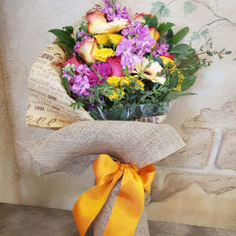 Mixed bouquet of roses, daisies, and purple flowers wrapped with burlap and ribbon