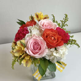 Mixed bouquet of roses, carnations, and white blooms in a glass vase