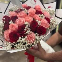 Bouquet of pink and red roses with baby's breath in white wrap