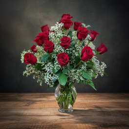 Red roses arranged in a clear glass vase with white baby's breath