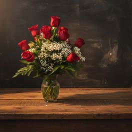 Red roses arranged in a clear glass vase with white filler flowers