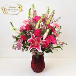 Pink and white mixed bouquet in a red glass vase