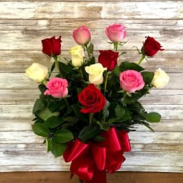 Bouquet of red, pink, and white roses with a red ribbon in a glass vase