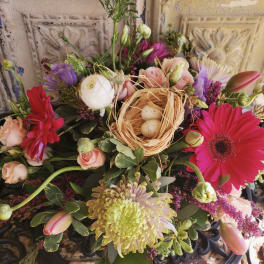 Mixed bouquet with pink gerberas, roses, and a small nest with eggs