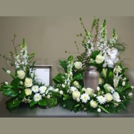 White floral funeral arrangement with a silver urn in the center