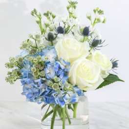 Blue hydrangeas and white roses in a clear glass vase
