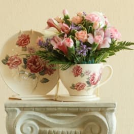 Pink floral bouquet in a floral teacup with matching saucer