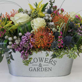 Mixed floral arrangement in a metal container with white roses and colorful blooms