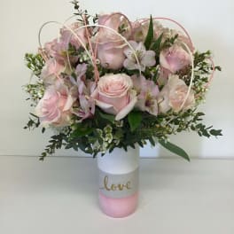 Pink rose bouquet in a white and pink vase with the word love