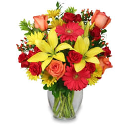 Mixed bouquet of roses, lilies, and daisies in a clear glass vase