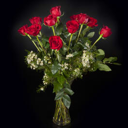 Red roses in a clear glass vase with small white filler flowers