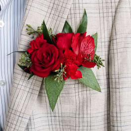 Red rose boutonniere with green leaves on a plaid jacket