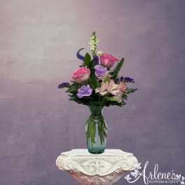 Pink roses and purple flowers arranged in a glass vase