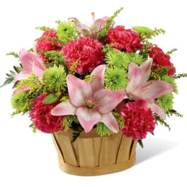Pink lilies and carnations in a wooden basket
