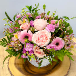 Pink roses and mixed blooms arranged in a white bowl vase