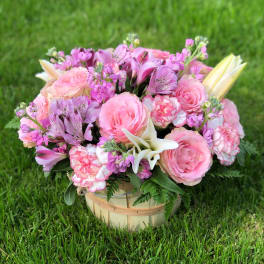 Pink and lavender flower arrangement in a wooden basket