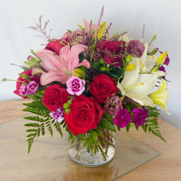 Mixed bouquet of roses, lilies, and carnations in a glass vase