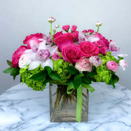 Pink roses and white orchids in a clear square vase