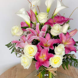 Pink lilies and white roses arranged in a glass vase