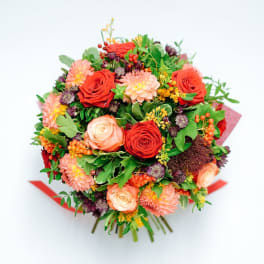 Round bouquet of red and peach roses with orange and pink blooms and berries