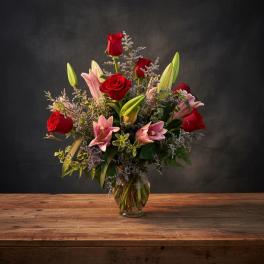 Red roses and pink lilies arranged in a glass vase
