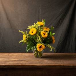 Sunflower bouquet in a clear glass vase on a wooden table