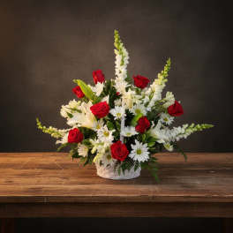 Basket arrangement of red roses, white lilies, and white daisies