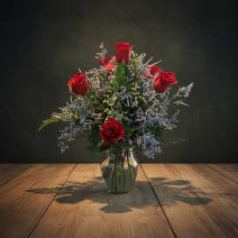 Red roses arranged in a clear glass vase with airy filler flowers