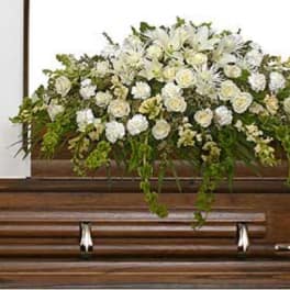 White floral casket spray on a wooden casket