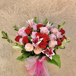 Bouquet of red and pink roses with lilies in a glass vase