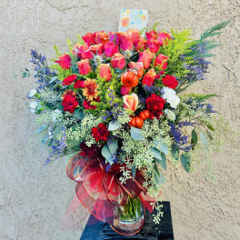 Large bouquet of pink roses and mixed flowers in a glass vase with a red ribbon
