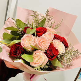 Bouquet of red and blush roses wrapped in pink paper